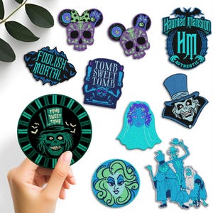 May include: A collection of embroidered patches featuring Haunted Mansion themes, including skull icons, text reading Foolish Mortal and Tomb Sweet Tomb, a ghost bride, a top-hatted character, and a group of figures in blue and green tones.