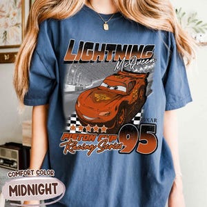 May include: Midnight blue t-shirt featuring Lightning McQueen from the Pixar Cars movie. The graphic includes the text "Lightning McQueen", "Piston Cup Racing Series", and the number "95". The shirt is labeled "Comfort Color".