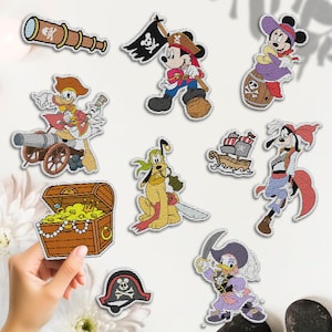 May include: A collection of embroidered patches featuring cartoon characters in pirate attire. Includes Mickey Mouse, Minnie Mouse, Donald Duck, Goofy, and Pluto. Other patches include a treasure chest, a spyglass, a pirate ship, and a pirate hat.