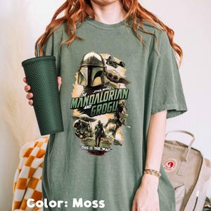 Puede incluir: Una camiseta verde musgo con un gr&aacute;fico de la serie Star Wars, "The Mandalorian and Grogu". El dise&ntilde;o incluye im&aacute;genes del Mandaloriano, Grogu y otros personajes, con la frase "This is the Way".
