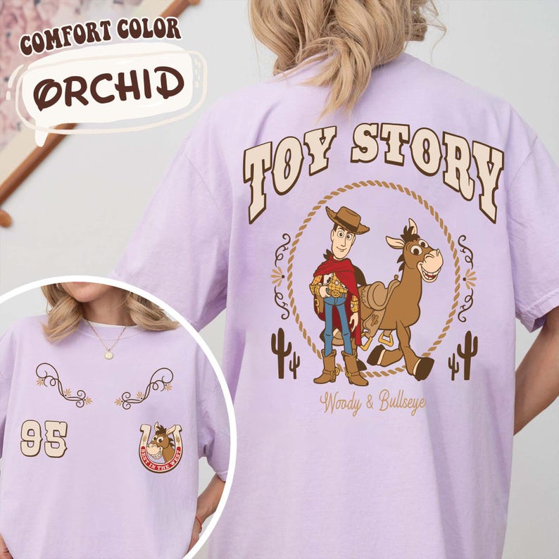 May include: Orchid-colored t-shirt featuring a "Toy Story" graphic on the back with Woody and Bullseye. The front of the shirt has a "95" graphic and a horseshoe with a horse. The shirt is a Comfort Color brand.