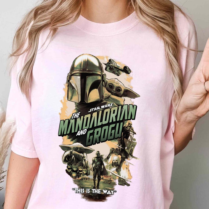 Puede incluir: Camiseta rosa claro con un dise&ntilde;o gr&aacute;fico de la serie Star Wars, "The Mandalorian y Grogu." El dise&ntilde;o incluye el casco del Mandaloriano, Grogu y la frase "This is the Way."