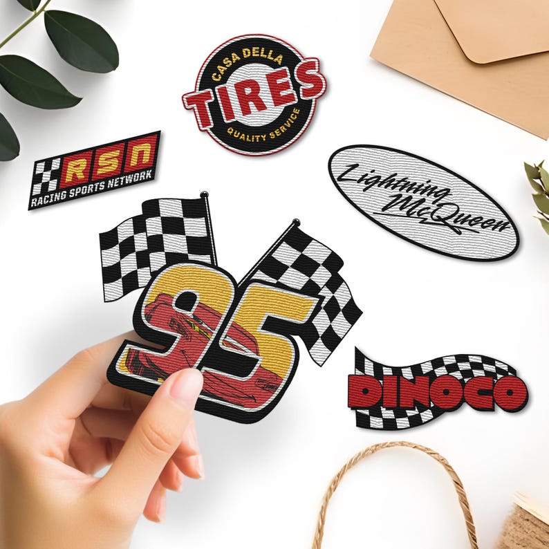 K&ouml;nnte beinhalten: Gestickte Aufn&auml;her mit Rennsportmotiven. Designs umfassen "Casa Della Tires", "Racing Sports Network", "Lightning McQueen", "Dinoco" und die Nummer "95" mit Rennflaggen. Die Aufn&auml;her sind in verschiedenen Farben gehalten, darunter Rot, Schwarz und Gelb.