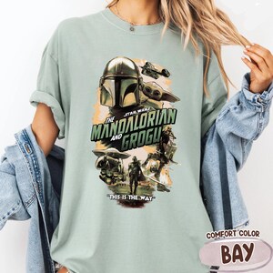 Puede incluir: Camiseta verde claro Comfort Colors con un gr&aacute;fico de Star Wars de "The Mandalorian and Grogu". El dise&ntilde;o incluye el casco del Mandaloriano, Grogu y la frase "This is the Way".