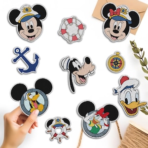 May include: A collection of embroidered patches featuring Disney characters in nautical themes. Includes Mickey Mouse, Minnie Mouse, Goofy, Donald Duck, Pluto, an anchor, a compass, and a life preserver. The patches are colorful and detailed, with a stitched border.