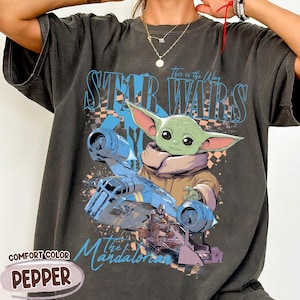May include: Dark gray Comfort Colors t-shirt featuring a graphic of Grogu from The Mandalorian, with the text "Star Wars" and "This is the Way." The design includes a blue spaceship and the word "Pepper."