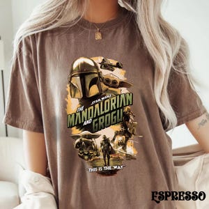 Puede incluir: Camiseta color espresso con un gr&aacute;fico de la serie Star Wars, "The Mandalorian and Grogu". El dise&ntilde;o incluye el casco del Mandaloriano, Grogu y otros personajes. Tambi&eacute;n est&aacute; presente el texto "THIS IS THE WAY".