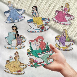 May include: Set of ten embroidered iron-on patches featuring Disney princesses in teacups. Each patch features a different princess, including Cinderella, Snow White, Ariel, Belle, Jasmine, and more. The patches are perfect for adding a touch of Disney magic to your clothing, bags, or other accessories.