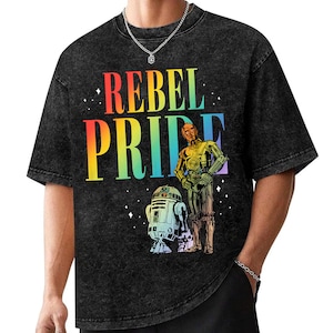 May include: Black t-shirt with a distressed look featuring a rainbow graphic that says "Rebel Pride". The graphic also includes a cartoon image of C-3PO and R2-D2.