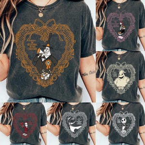 May include: A selection of dark grey t-shirts featuring characters and designs from "The Nightmare Before Christmas." Each shirt displays a different character or scene within a decorative heart-shaped frame. The shirts are made of a soft material.