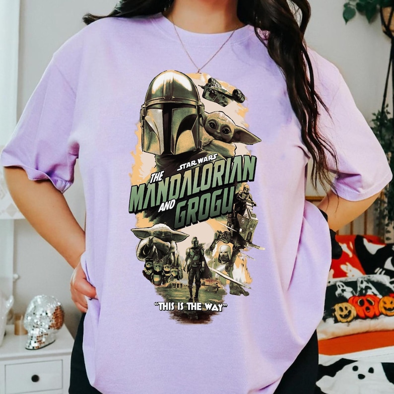 Puede incluir: Una camiseta de color lila claro con un dise&ntilde;o gr&aacute;fico de la serie Star Wars, "The Mandalorian and Grogu". El dise&ntilde;o incluye im&aacute;genes de The Mandalorian, Grogu y otros personajes, con la frase "THIS IS THE WAY."