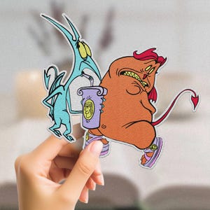 May include: A blue and orange cartoon character with a red devil tail and horns. The character is wearing a purple and white cup with a cartoon face on it. The character is holding a blue and white cartoon character with a long tail and horns.