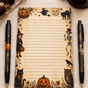 May include: A rectangular notepad with horizontal lines and a vintage-style border featuring illustrations of a jack-o'-lantern, a witch on a broom, a moon, a black cat, a child in a costume, a skeleton, a crow, and an owl, flanked by two black pens.