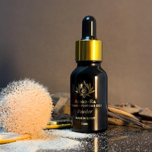 May include: A black glass bottle with a gold lid and dropper. The bottle is labelled "Amon-Ra Premium Perfume Oils Powder Made in Egypt 15ML".