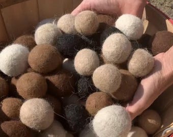 May include: A basket filled with a variety of wool dryer balls in beige, brown, and black colors.