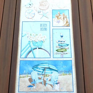 May include: A rectangular beach-themed artwork featuring various blue and beige watercolor illustrations. The artwork includes images of seashells, a bicycle with flowers, a beach scene with chairs and an umbrella, and the text "BEACH BOUND".