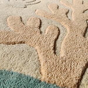 May include: A tufted area rug featuring a textured, raised coral design in beige against a cream background. The rug includes light blue fish and yellow sea life motifs, with the text Indian Art & Decor printed in the bottom right corner.