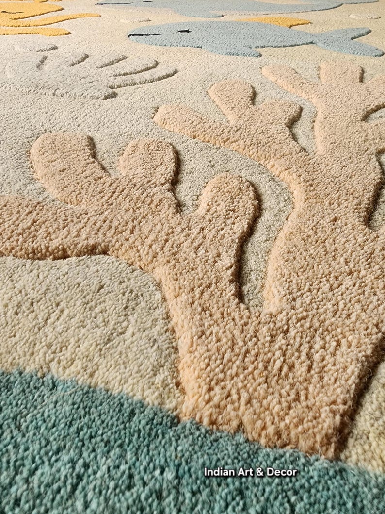 May include: A tufted area rug featuring a textured, raised coral design in beige against a cream background. The rug includes light blue fish and yellow sea life motifs, with the text Indian Art & Decor printed in the bottom right corner.