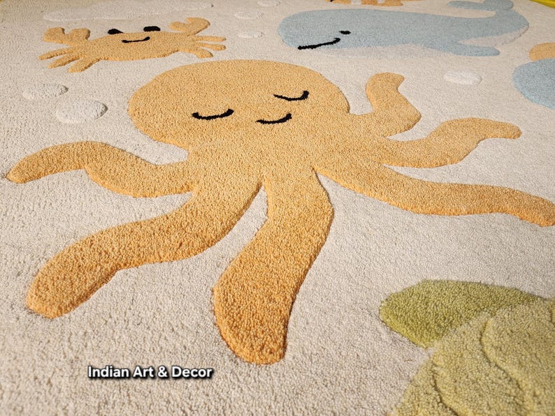 May include: A tufted area rug with an off-white background featuring a large yellow octopus, a light blue whale, a yellow crab, and a green sea turtle. The design includes small circular bubble shapes and the text Indian Art & Decor.
