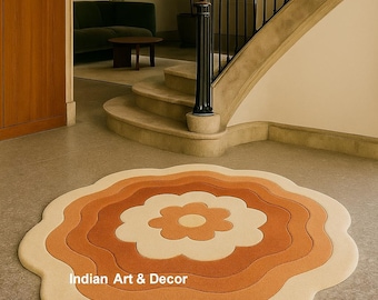 May include: A floral-shaped area rug in shades of cream, orange, and brown. The rug is placed on a gray floor in a home setting. The text "Indian Art & Decor" is visible on the rug.