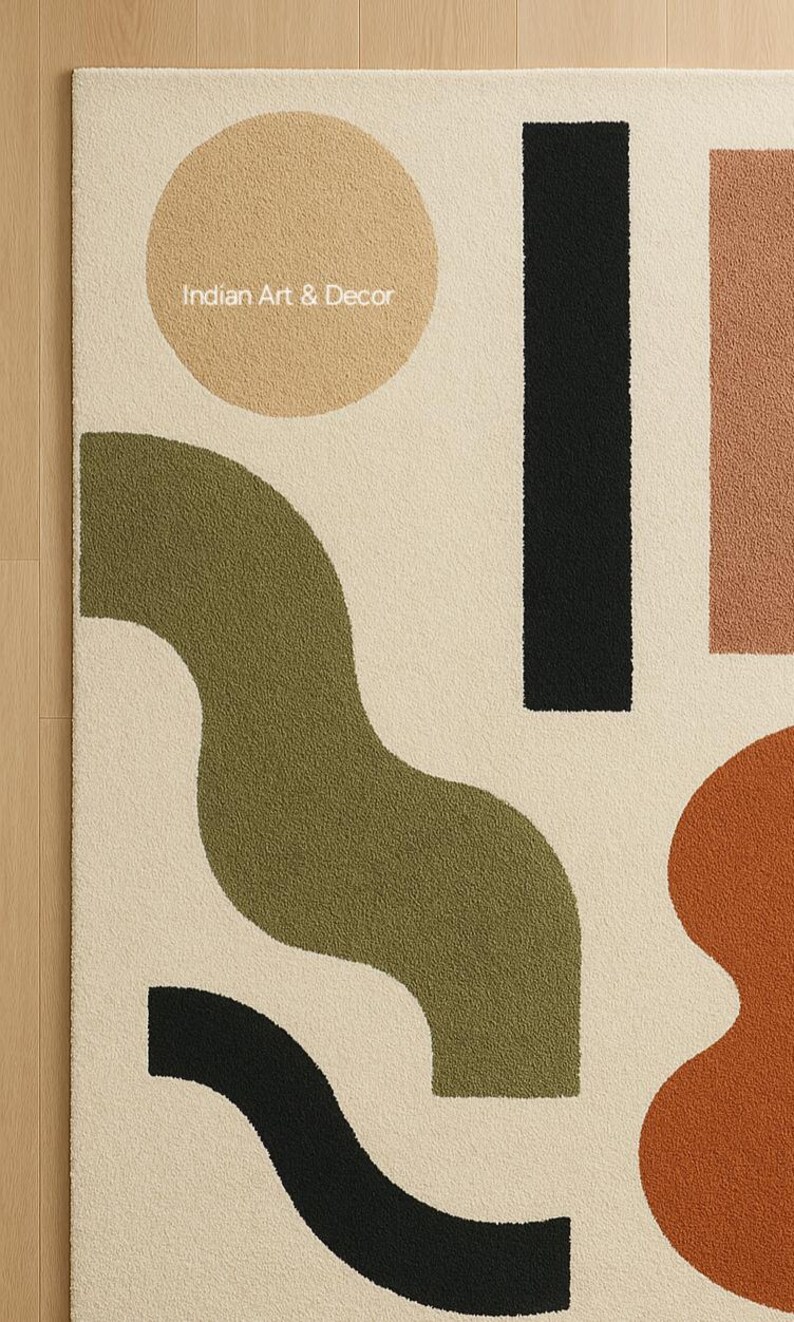 K&ouml;nnte beinhalten: Cremefarbener Teppich mit einem abstrakten Design mit einem beigen Kreis, einem schwarzen Rechteck und olivgr&uuml;nen und rostfarbenen organischen Formen. Der Text "Indian Art & Decor" ist auf dem Teppich zu sehen.