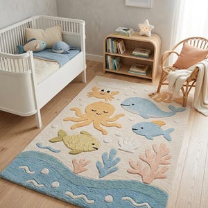 May include: A rectangular area rug featuring a cream-colored background with a tufted ocean theme. The design includes a light blue wave border at the bottom, a yellow octopus, a light blue whale, a yellow fish, a crab, and coral accents.