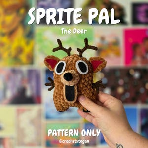 May include: A brown crocheted deer plush toy with dark brown antlers, large white and black eyes, and a wide open black mouth. The text SPRITE PAL The Deer PATTERN ONLY @crochetxtegan is visible in white lettering against the background.