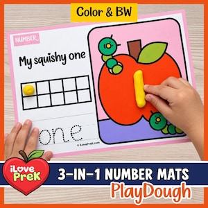 Op de afbeelding: Een rechthoekige educatieve mat met de tekst My squishy one, een tienerframe met een gele kleibal, het gestippelde woord one en een grote rode appelillustratie met twee groene rupsen en een gele klei-cijfer één.