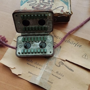 May include: A vintage Klingenschärfer Sieger blade sharpener in a brown case with green inserts and two black knobs. The device includes a cardboard box with illustrated text and a paper instruction manual featuring the text Gebr. Schmidt Zella-Mehlis.