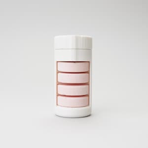 Könnte beinhalten: Ein weißer Pillenorganizer aus Kunststoff mit fünf Fächern, gefüllt mit rosa Pillen.