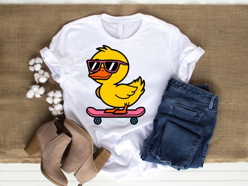 May include: A white t-shirt with a cartoon image of a yellow duck wearing sunglasses and riding a pink skateboard.