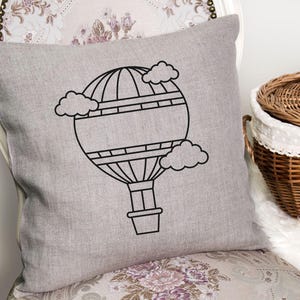 May include: A gray throw pillow with a black outline of a hot air balloon with clouds. The balloon has a basket and is surrounded by clouds.