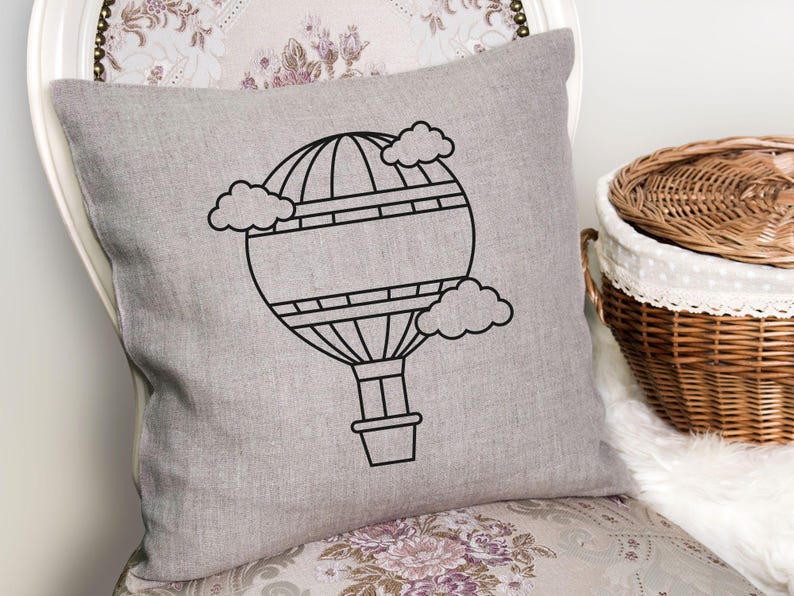 May include: A gray throw pillow with a black outline of a hot air balloon with clouds. The balloon has a basket and is surrounded by clouds.