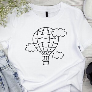 May include: White t-shirt with a black outline of a hot air balloon and clouds.