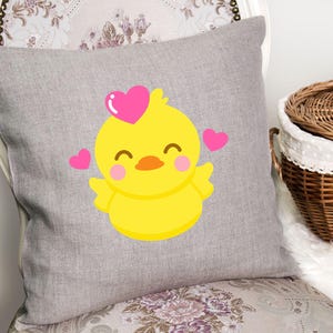 May include: A gray pillow with a yellow chick with pink hearts on a gray background.