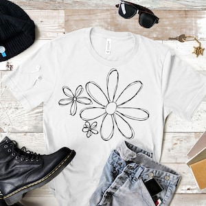 Pode incluir: Camiseta branca com um contorno preto de tr&ecirc;s margaridas. As margaridas s&atilde;o estilizadas e t&ecirc;m um design simples.