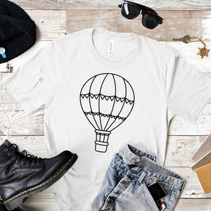 May include: White t-shirt with a black outline of a hot air balloon. The balloon has a basket and a pattern of triangles around the top.