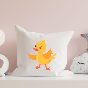 May include: White pillow with a yellow duckling cartoon illustration. The duckling is facing right and has a red beak and orange feet.