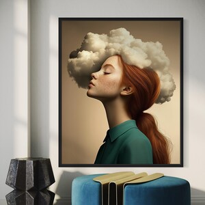 May include: A framed art print depicting a woman with red hair and freckles, looking upwards with closed eyes. A cloud is positioned above her head. She wears a green collared shirt. The artwork is set against a neutral background.