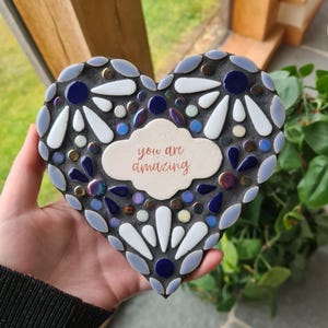 May include: A heart-shaped mosaic tile with a white background and blue and white flower designs. The tile has a white cloud-shaped tag with the text "you are amazing" in cursive.