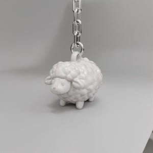 May include: A white ceramic sheep keychain with a silver chain. The sheep has a fluffy texture and a cute face.