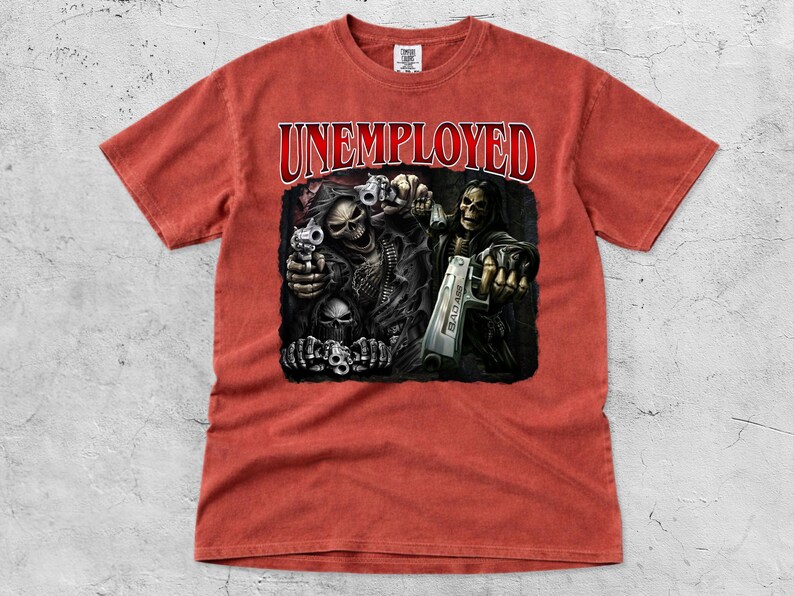 May include: A red-orange t-shirt featuring the word "UNEMPLOYED" in red, arched text. The graphic depicts skeletal figures holding guns. The design is printed on a soft, short-sleeved tee.