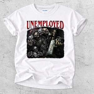May include: White t-shirt with a graphic featuring skeletal figures holding guns, with the word "UNEMPLOYED" in red above. The design is detailed with dark shading, creating a dramatic effect. The shirt is made of a soft material.