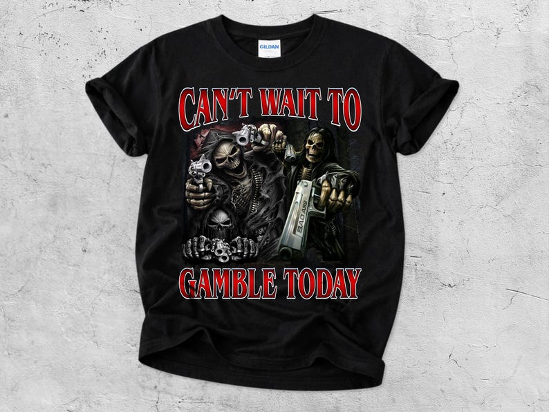 May include: Black t-shirt with a graphic featuring skeletal figures holding guns. The text "CAN'T WAIT TO GAMBLE TODAY" is printed in red, outlined in white. The shirt is made of a soft material.
