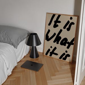 It Is What It Is poster in beige and black with a handwritten quote design. Modern wall art for calm, chill vibes and effortless style. Perfect for living room, office, or bedroom decor.