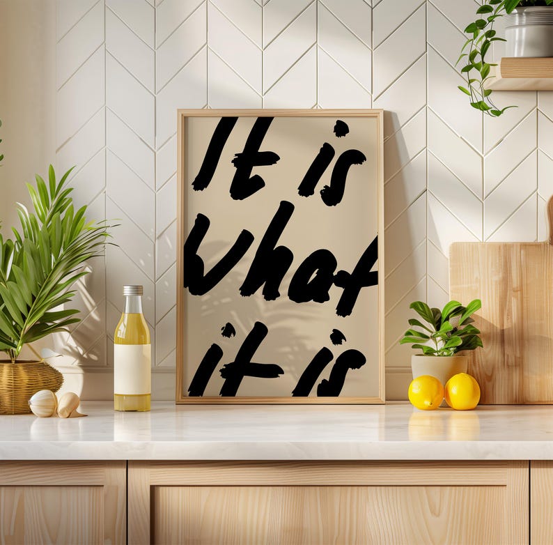 It Is What It Is poster in beige and black with a handwritten quote design. Modern wall art for calm, chill vibes and effortless style. Perfect for living room, office, or bedroom decor.