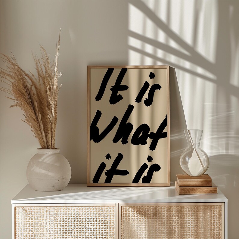 It Is What It Is poster in beige and black with a handwritten quote design. Modern wall art for calm, chill vibes and effortless style. Perfect for living room, office, or bedroom decor.