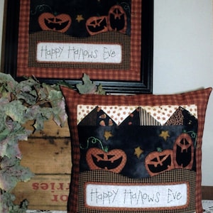 May include: A framed Halloween-themed wall hanging and a matching pillow. Both feature jack-o'-lanterns, stars, and the text "Happy Hallows Eve" on a black background. The frame and pillow have a plaid border.