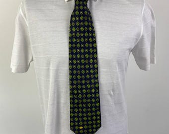 Puede incluir: Una corbata azul oscuro con un patrón repetido de cuadrados y círculos verdes y dorados.
