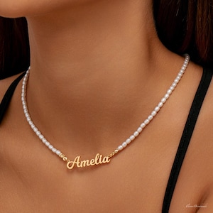 Può includere: Una delicata collana di perle con un ciondolo con il nome in oro che recita "Amelia".